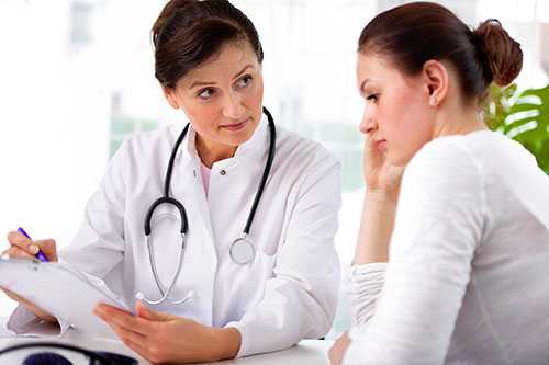 Female doctor holding a clipboard talking with a female patient