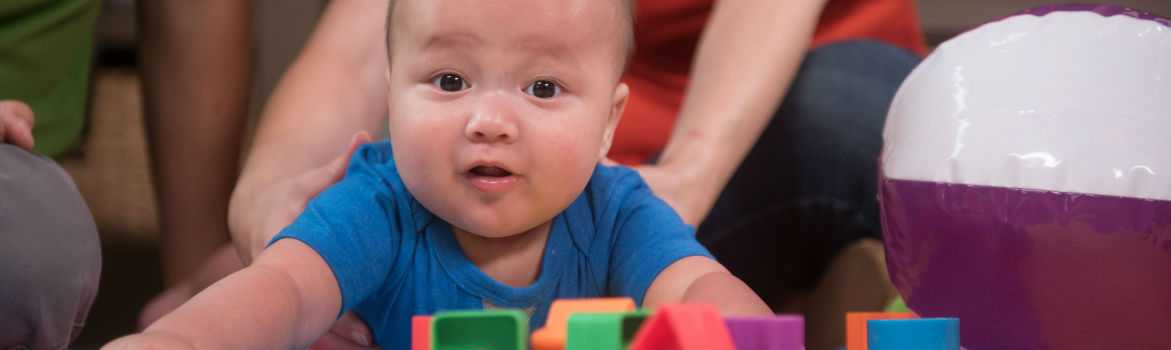 Baby being held up while playing with blocks