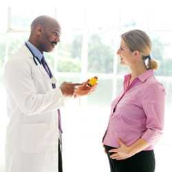 Doctor holding medicine talking with pregnant woman