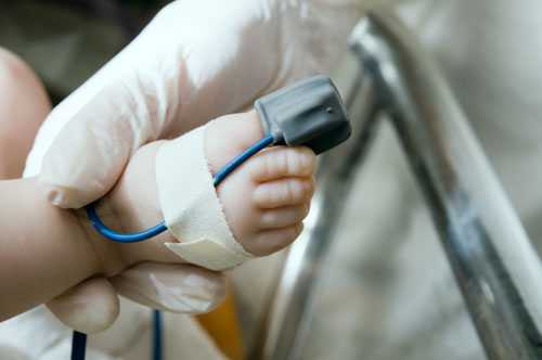 Infant with a pulse oximeter on its toe