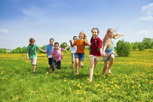 Photo of diverse kids running in grass together.