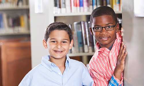 Dos niños sonriendo en la biblioteca