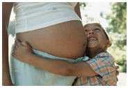 Un niño pequeño abrazando el vientre de su mamá embarazada