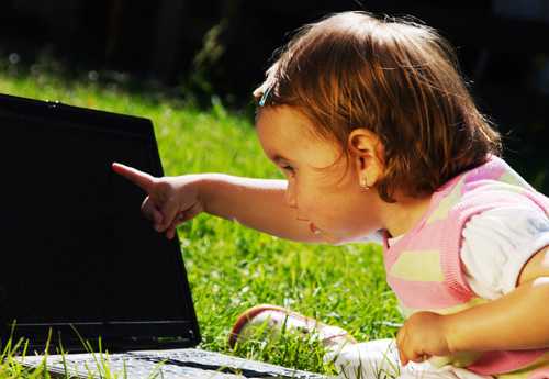 Toddler pointing at a laptop.