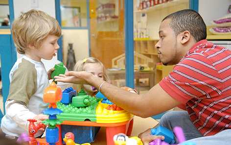 An early education provider plays with two children.