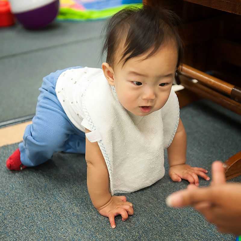 A baby crawls across the floor.