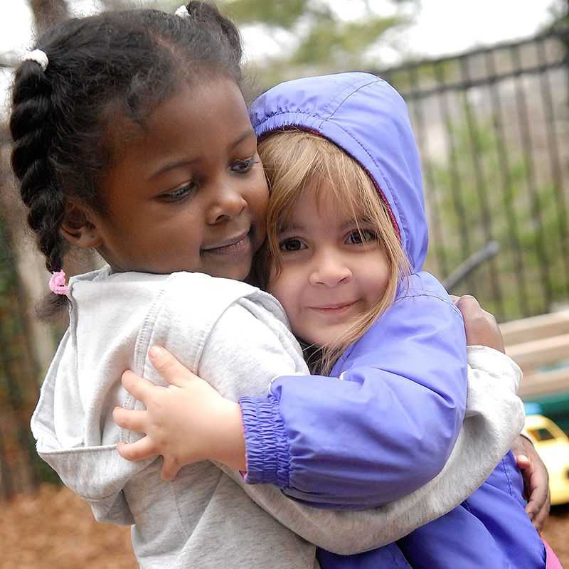 Two girls hug on the playground.