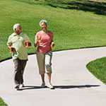 	A man and woman walking on a paved trail.