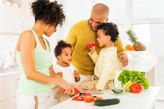 	African American family prepares vegetables in kitchen.