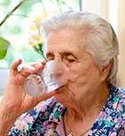 Photo of an elderly woman drinking a glass of tap water.