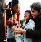 Image of a Latino family at an outside water faucet.