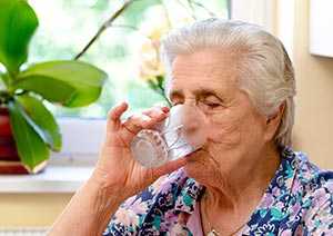 Photo of an elderly woman drinking a glass of water.