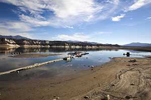Shrinking water supply in lake reveals drying, cracked shoreline.