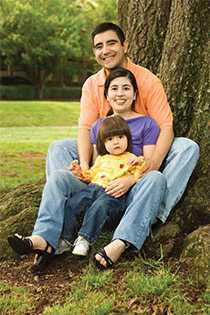 Hispanic family outside sitting in front of a tree