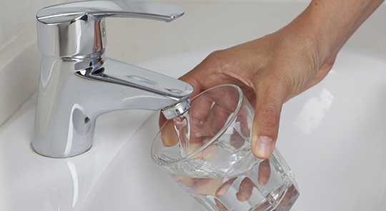 hand filling glass with water from a faucet