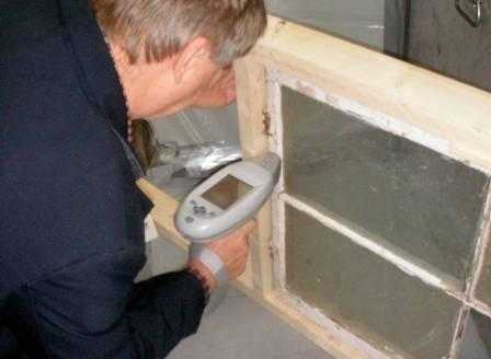 XRF machine being used to test for lead on a window frame that has chipping and peeling paint.