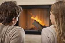 man and woman sitting in front of fireplace with burning logs