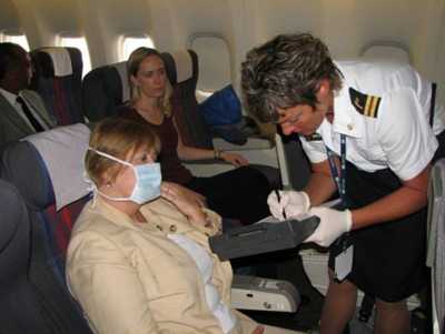 Quarantine station worker interviewing a passenger wearing a mask on a plane