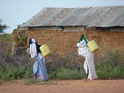 Two women carrying containers of water