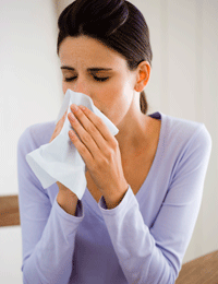 Woman covering her nose and mouth with her sleeve while sneezing.