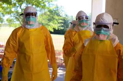 Image of people in yellow protective gear, complete with face masks and head covering.