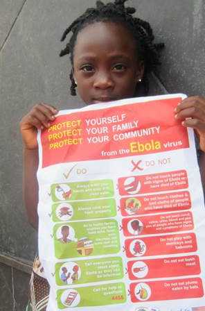 Image of a young girl holds a poster about Ebola protection