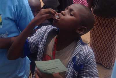 Young boy drinking a cholera vaccine from a small bottle