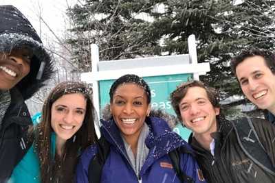 Group of young scientists bundled in winter geer but smiling at the camera while snow falls