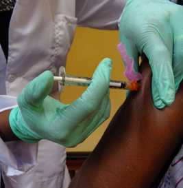 doctor with gloved hands giving a vaccine to someone's arm
