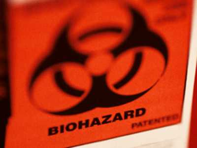 An orange biohazard label on a bright red container.