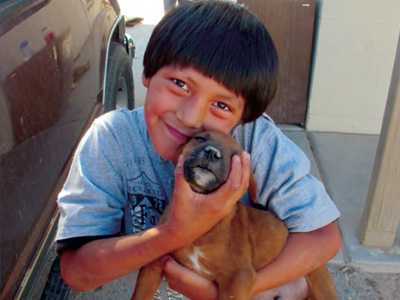 A smiling boy holding a little brown puppy