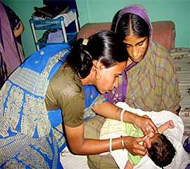 Two community health workers assess a newborn
