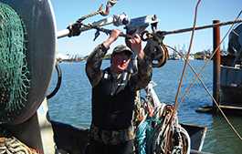 	12-year commercial fishing veteran Brett Smith works the line in the Rogue flotation vest created by Kent Safety Products. Photo courtesy of Kent Safety Products.