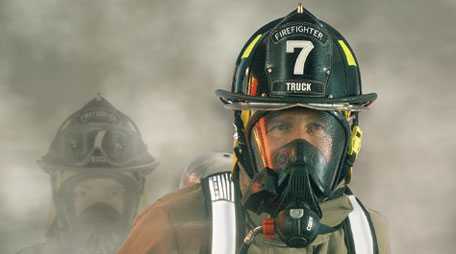 Firefighter wearing personal protective ensemble and self-contained breathing apparatus.