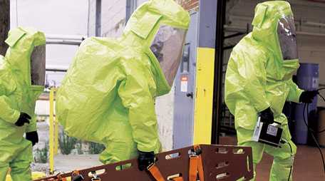 Hazmat technicians entering a building wearing protective ensembles.