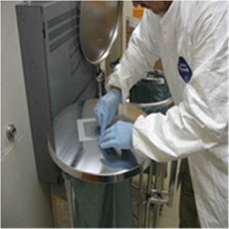 A person in protective laboratory geat works on a sample