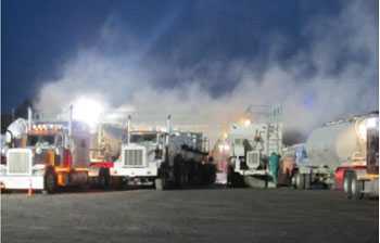 Clouds of dust are visible as sand trucks are unloaded at a hydraulic fracturing site. 