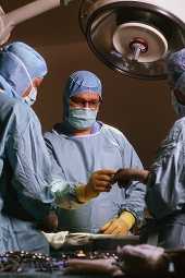 health care workers exchanging an instrument during surgery