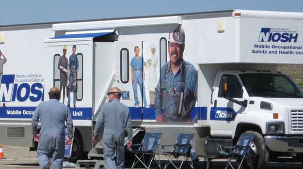 Two miners approach a NIOSH mobile health unit