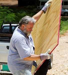 2 men caring a large panel of plywood