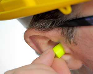 	A worker placing an earplug into his ear