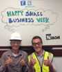 	Two people giving thumbs-up infront of a whiteboard which says Happy Small Business Week
