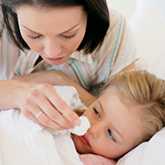 mom wiping sick child's face with tissue