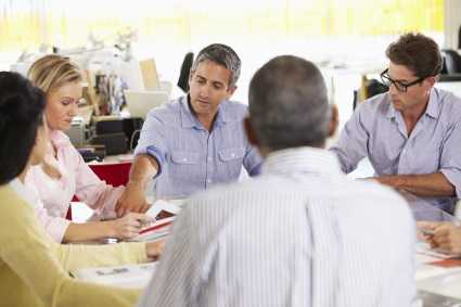 Group of 5 people at a table having a meeting.