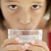 Primer plano de una niña tomando agua de un vaso