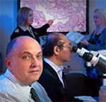 Pathologists examine and discuss a specimen using high power microscopes