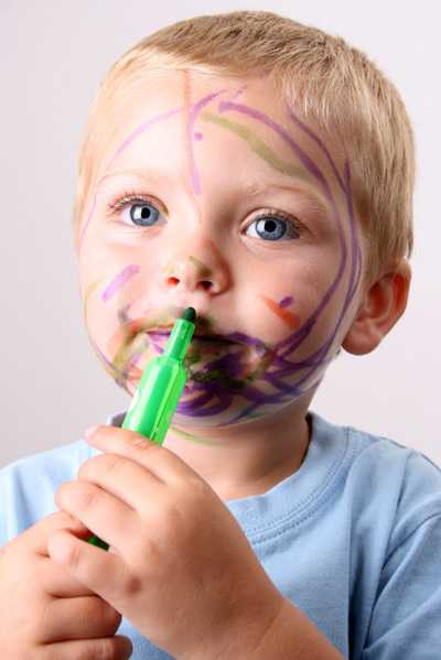 Young boy drawing on his face with a marker