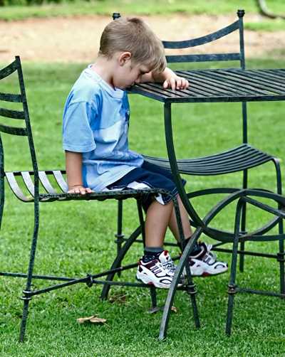 Boy with head down on outside table