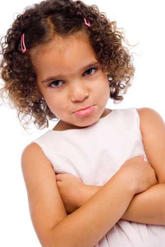 Young girl with curly hair frowning with arms crossed