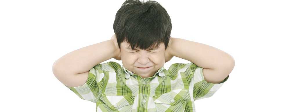Image of a young boy covering his ear to block loud noise 